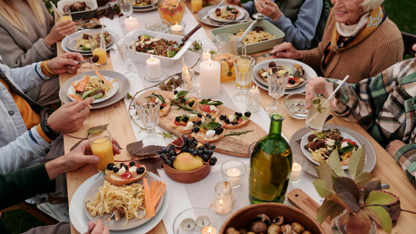 Table with place settings and food and several seated guests around it