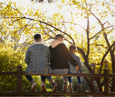 full-shot-lgbt-family-sitting-outdoors 1